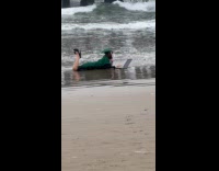 Woman toga lie down with laptop at beach