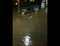 Water swirls in flood near parked cars 