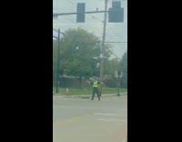 Black shirt safety vest guy directs traffic 