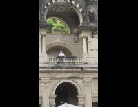 Woman poses on balcony of busy restaurant 