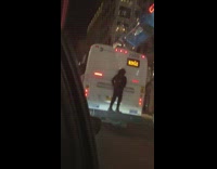 Guy stands on the back of moving bus