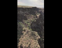 Brown mountain cliff overlooks river white clouds