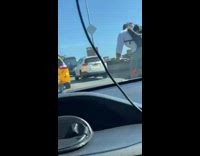 Man rides bicycle across bridge through traffic