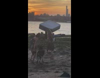 Guy carries air mattress near river 