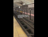 Subway maintenance workers lean against wall on train track