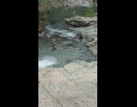 Woman poses in front of the small waterfall