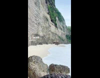 Girl sitting on beach rock high tide 