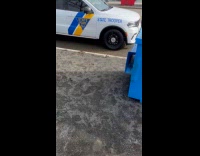 Woman shooting can on dumpster near police car 