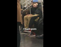 Guy sleeps on girlfriend leaning down on lap on subway train