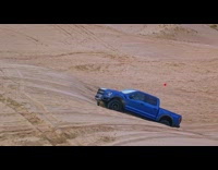 Guy drives blue truck up hill jumps 