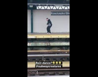 Guy dances at train metro station in the rain with headphones on