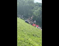 Shirtless guy in spandex shorts at park doing a funny dance 
