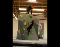 Woman short indoor climb while man on top films