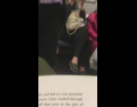 woman looks up from book to see couple talking on subway 