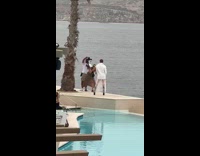 Person white suit poses by the pool