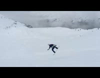 Guy snowboarding down mountain jumps and falls 