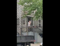 Guy stands by door blows conch horn 