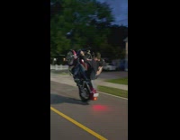 Guy does wheelie on motorcycle and scapes road
