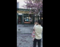 Girl brown coat spin beside tree flowers