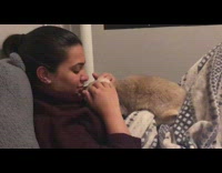 Collab Pets For All - Woman pets bunny rabbit laying on her chest on bed