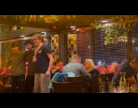 Three boys sing inside restaurant around customers