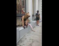 Man in rat costume squats on sidewalk 