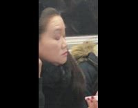 Woman puts on powder make up on ears with brush and compact mirror on subway train