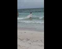 Woman in white beach dress poses on the beach shore