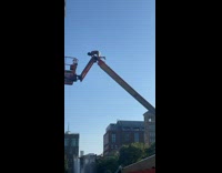 Guy on top of a high construction lift surrounded by police