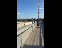 Man balancing tire on head riding bike on bridge