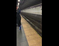 Woman has headphones on and happily dances by herself in subway station