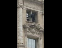 Man stands at the edge of a window and sticks his leg out