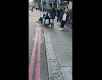 Woman in white sweater sits and poses on the sidewalk