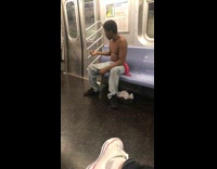 Shirtless guy talks to himself with pink scarf tied around hips on subway train