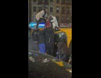 People on top of flipped taxi trying to pull driver out