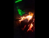 Person wave green laser on camp fire smoke