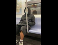 Guy sitting on subway train with beanie pulled over head