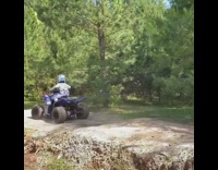 Little boy rides blue ATV over hill 
