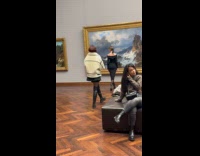 Woman black dress poses front of artwork