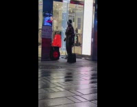 Guy in skeleton mask dancing to music on rainy day sidewalk