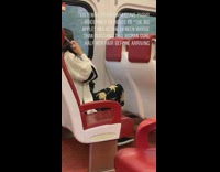 Woman uses curling iron to curl hair on metro train white sweater