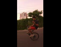 Red shorts guy wheelie half white bicycle 