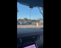 Man dances behind woman at parking lot