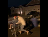 two guys on grey shopping cart racing down street