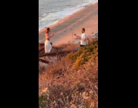 Man films woman in beach dress dance