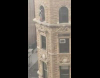 Guy stands outside on window ledge tall building 