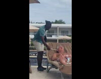 Guy in blue shirt tickling sleeping mans ear with white paper towel stick