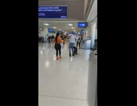 Guy rollerskates at airport while girlfriend dances