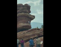 Woman white tank top hand stand rock