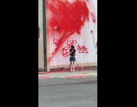 Woman hold knife beside wall vandalized with red